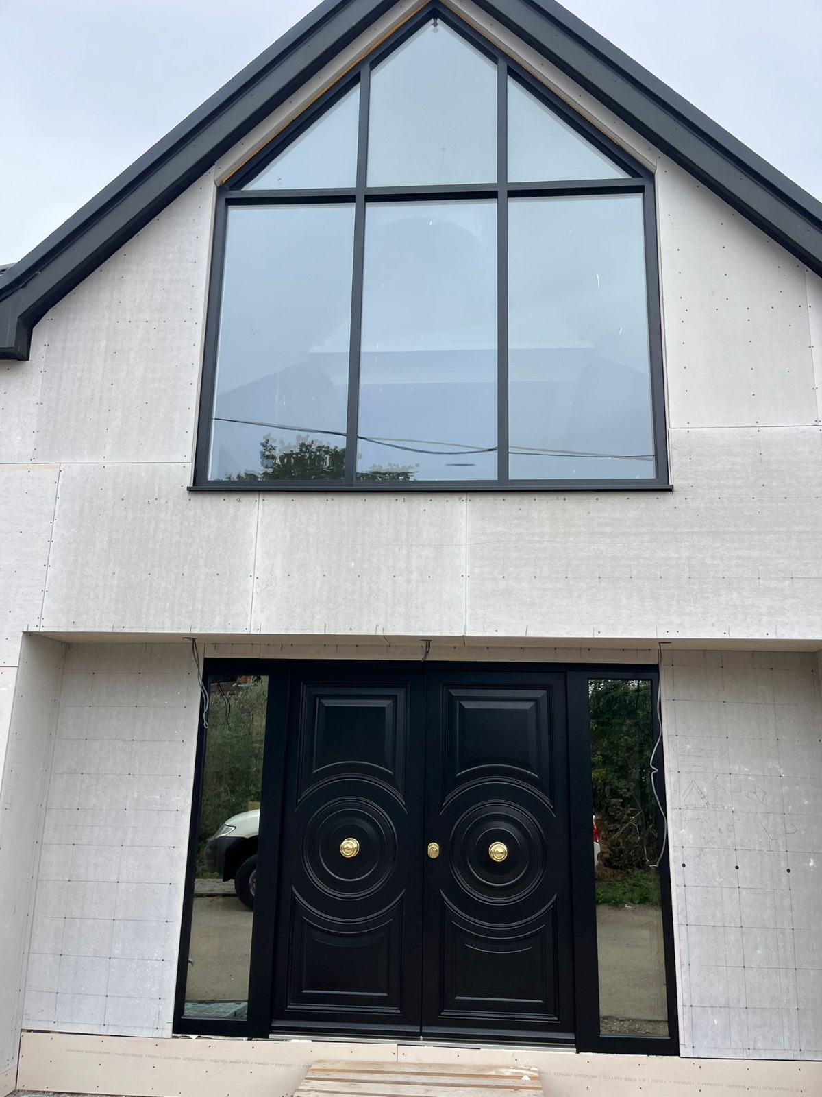 Black ornate double steel doors with gable entrance