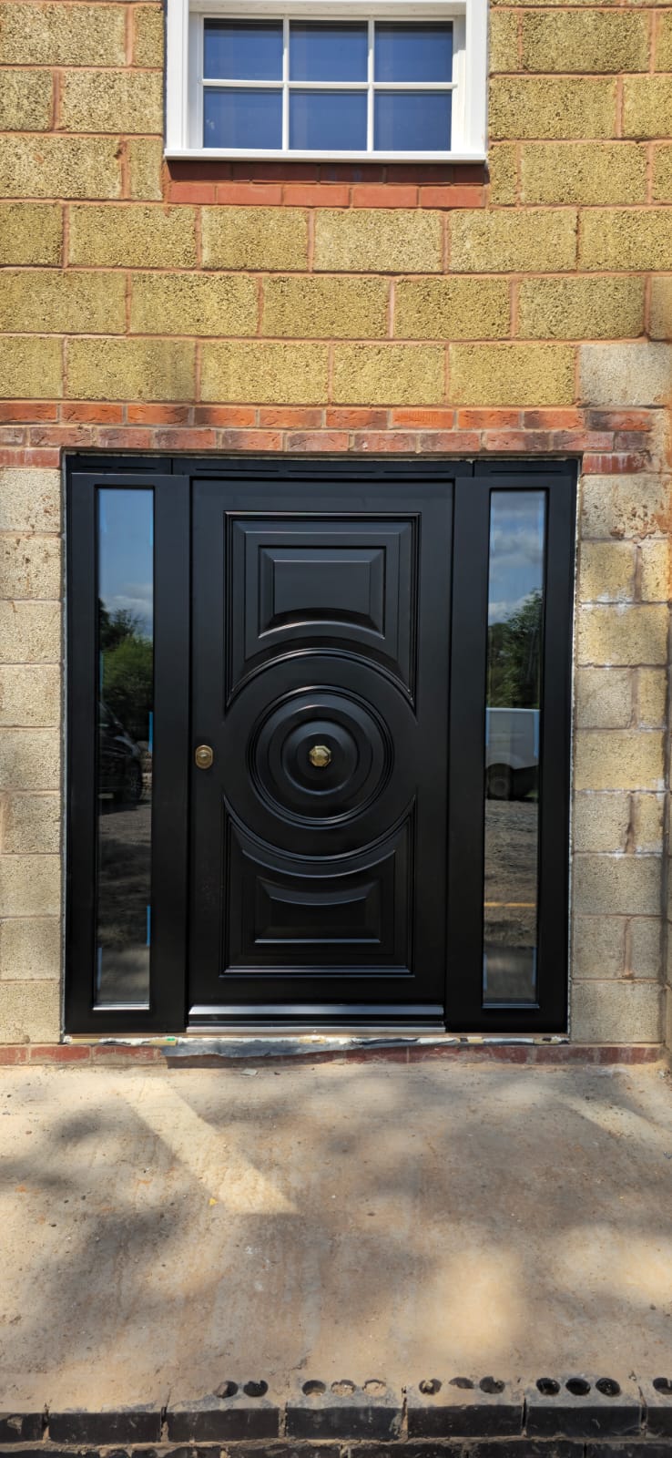 Black ornate steel door with medallion and sidelights