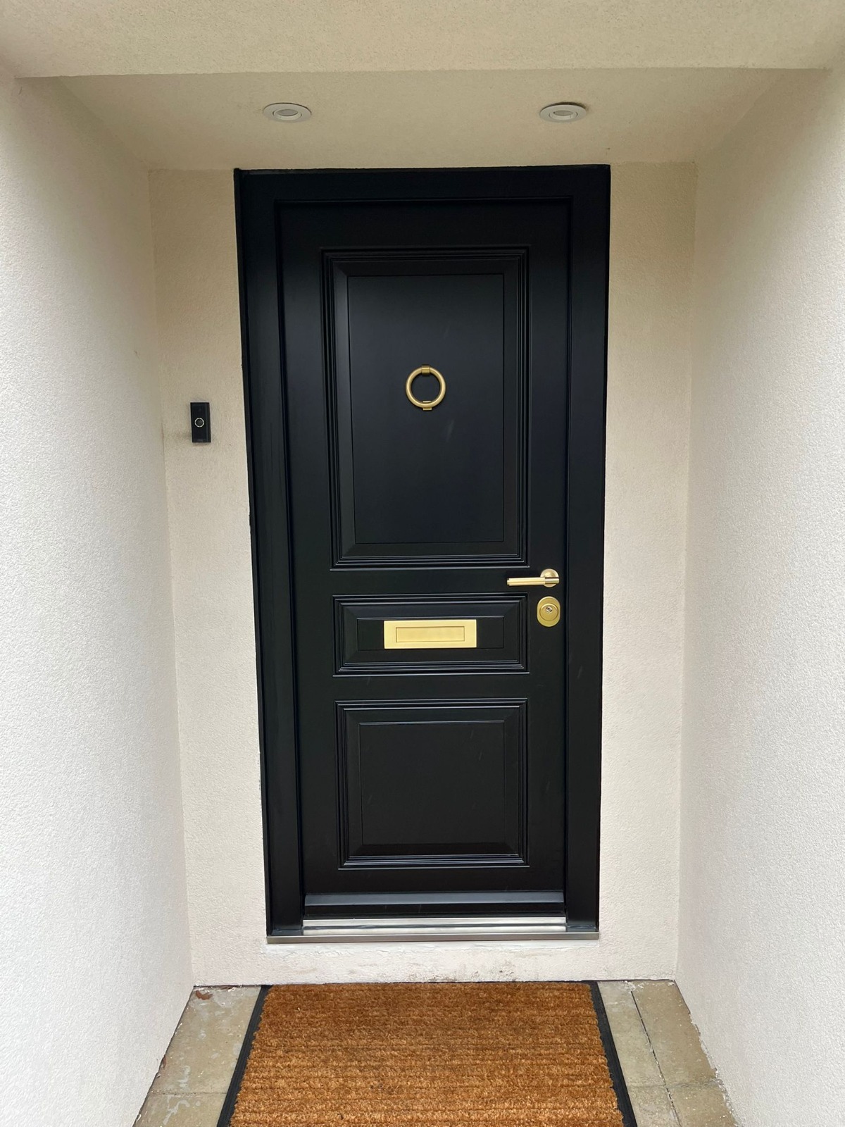Black panelled steel door with ring knocker recessed