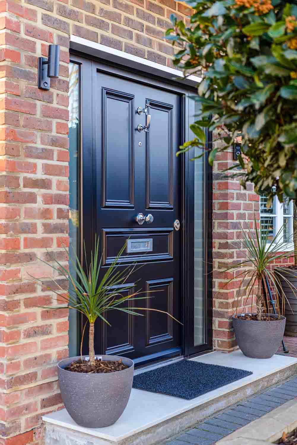 Navy panelled steel door with chrome hardware and palms