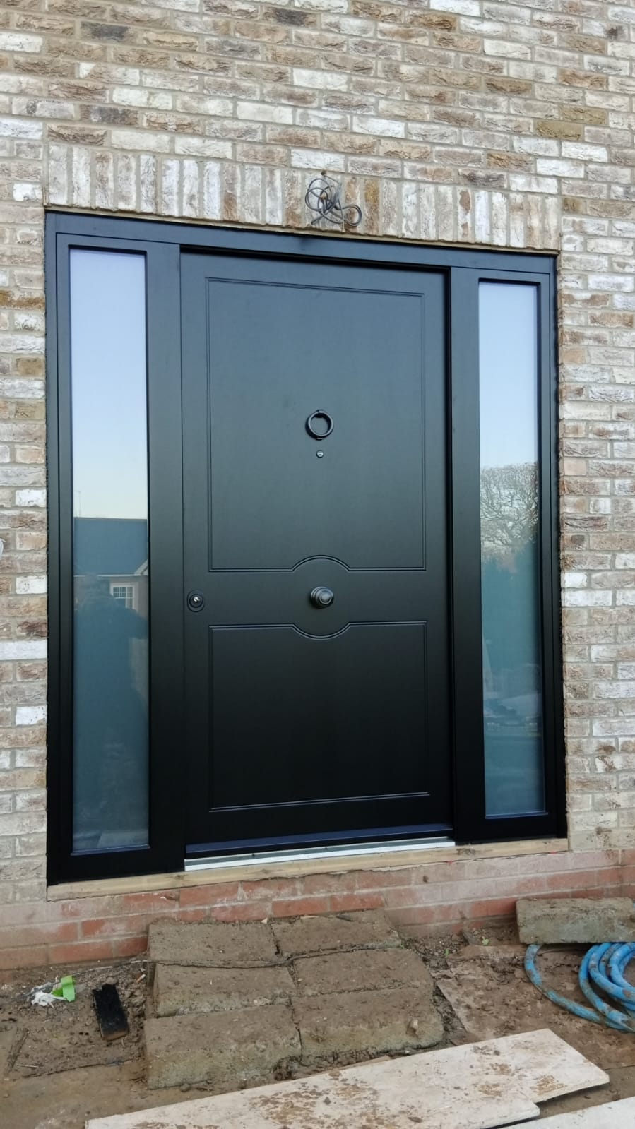 Black contemporary steel entrance door with dual sidelights — example of bespoke steel door design