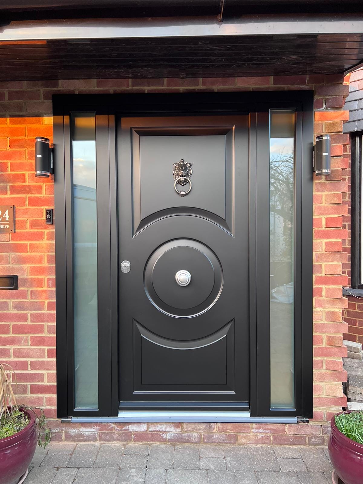Black ornate steel door with lion knocker and sidelights