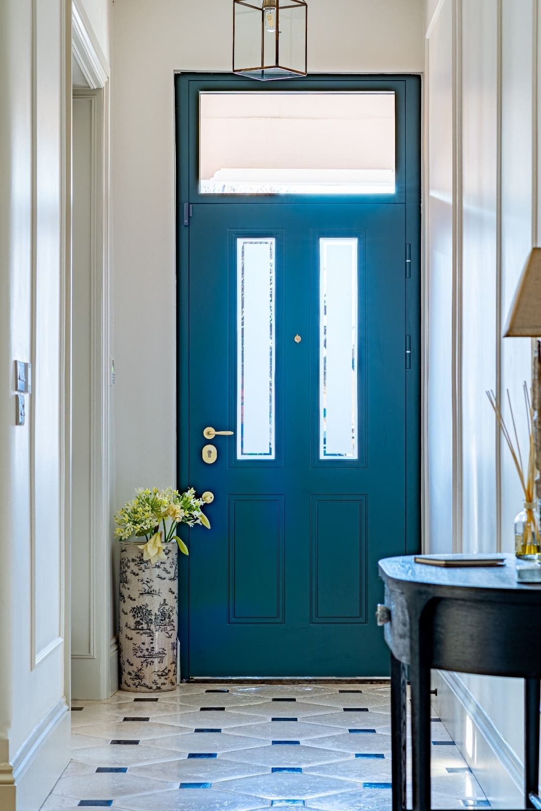 Teal panelled steel door with glass hallway